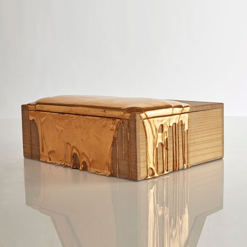 Contemporary wooden box with shiny gold detailing on a reflective surface.