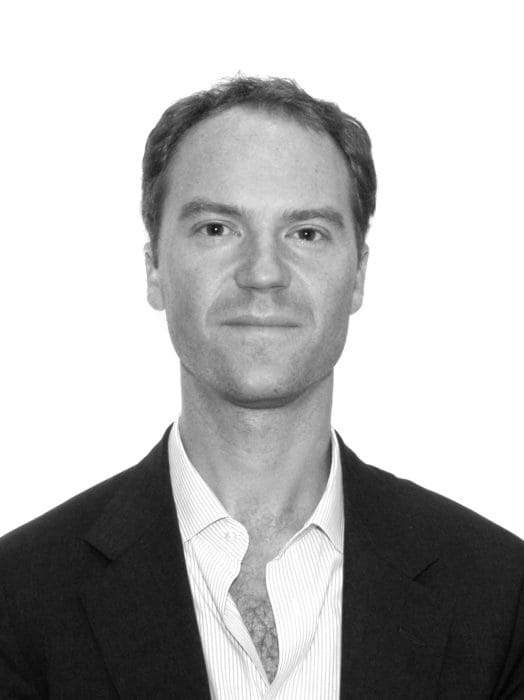 Man in suit with a light-colored shirt, facing forward, against a white background.