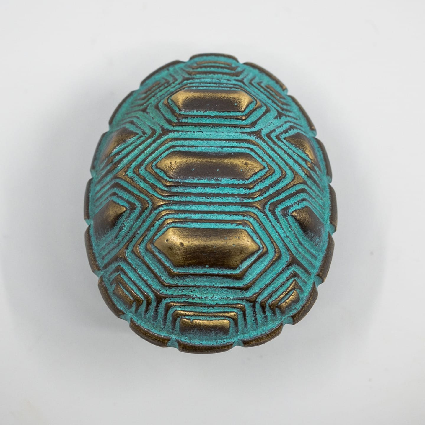 Ornate turquoise and brass scarab beetle with geometric patterns on a white background.