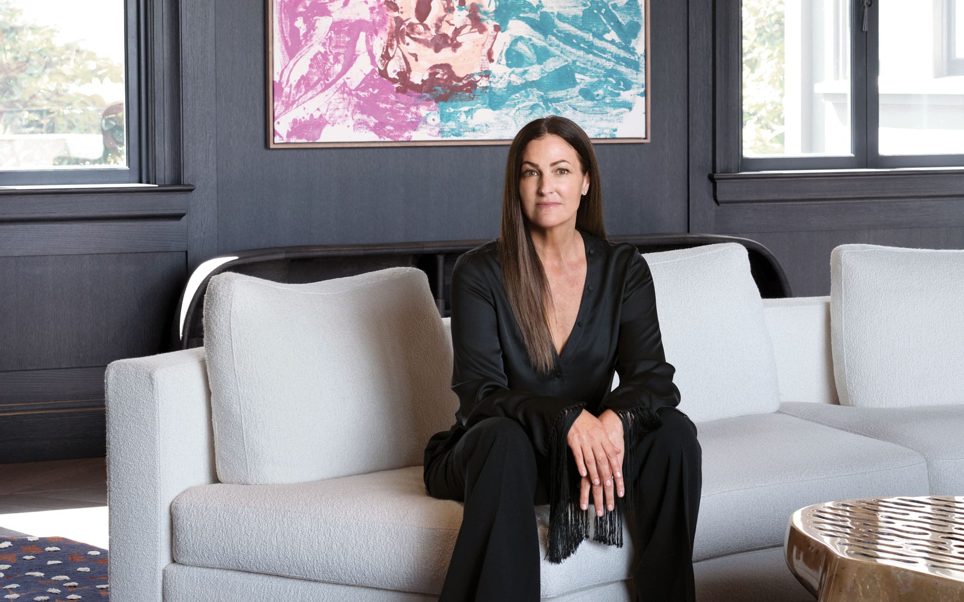 Person sitting on a white sofa in a modern living room with abstract art on the wall in the background.