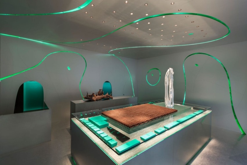 Futuristic museum exhibit with abstract design, featuring a central rectangular display surrounded by green ambient lighting.