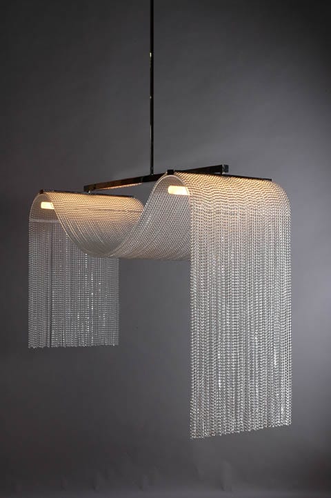 Modern chandelier with cascading metal chains and black frame on a dark background, emitting a soft glow.