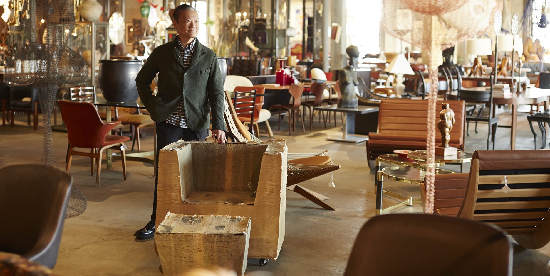 Man standing in a furniture showroom with various chairs and decorative items in the background.
