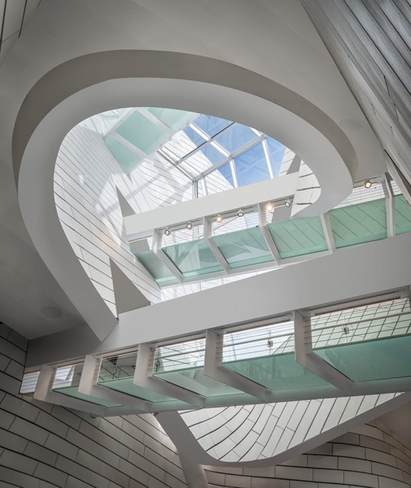 Futuristic architectural design with curved lines, large glass skylight, and modern interior space.