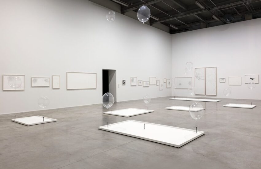 Modern art gallery with floating glass spheres and minimalist framed artwork on white walls.
