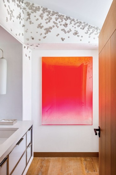 Bright red and pink gradient artwork on a white wall in a modern room with wooden flooring and ceiling decorations.