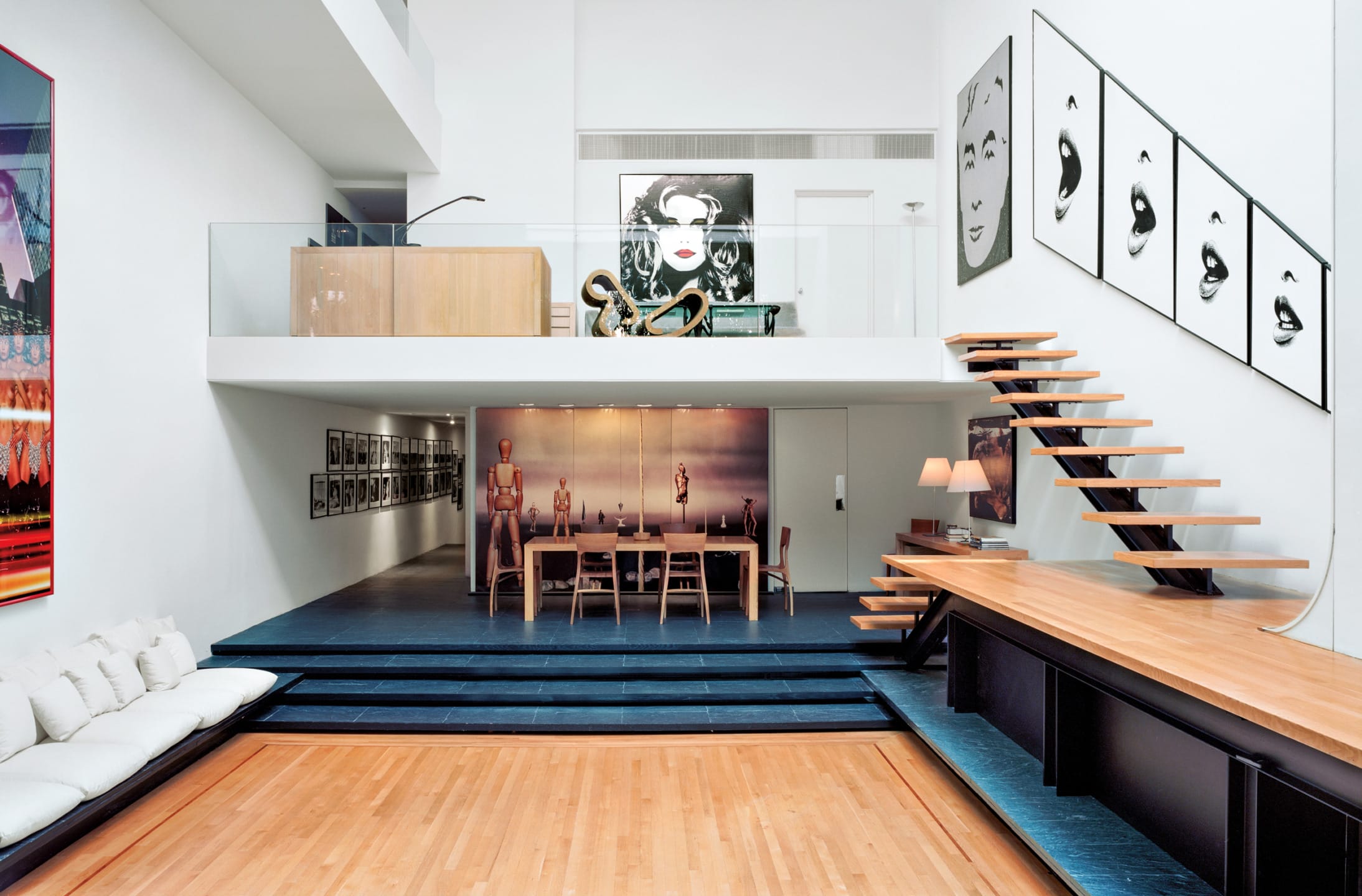 Modern living space with wooden floors, minimalist furniture, and framed artwork on white walls.