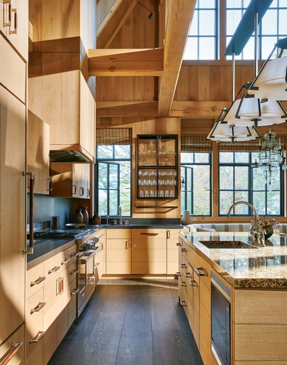 Spacious modern kitchen with wooden cabinets, island, granite countertops, and large windows with tree views.