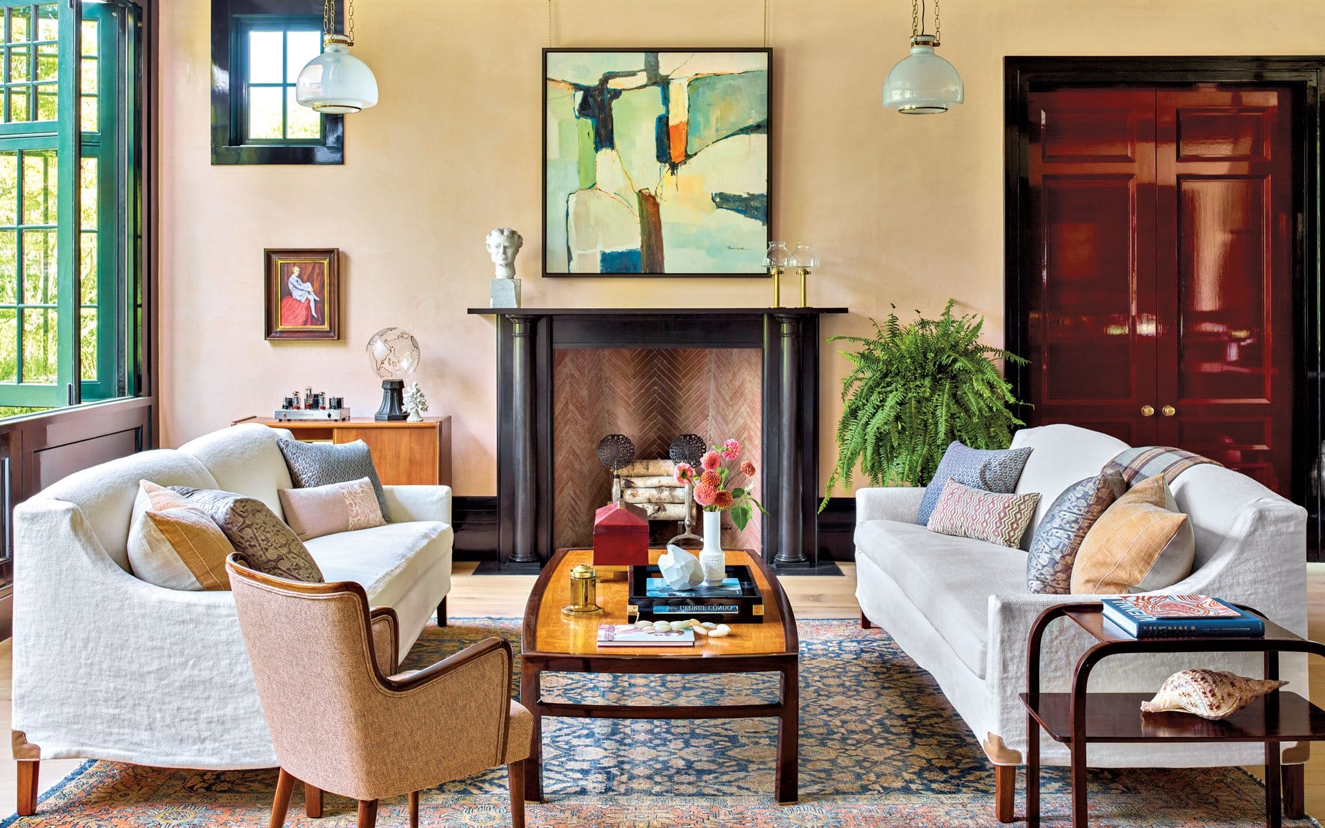 Bright living room with modern art, cozy sofas, a coffee table, and a fireplace, decorated with plants and stylish accents.