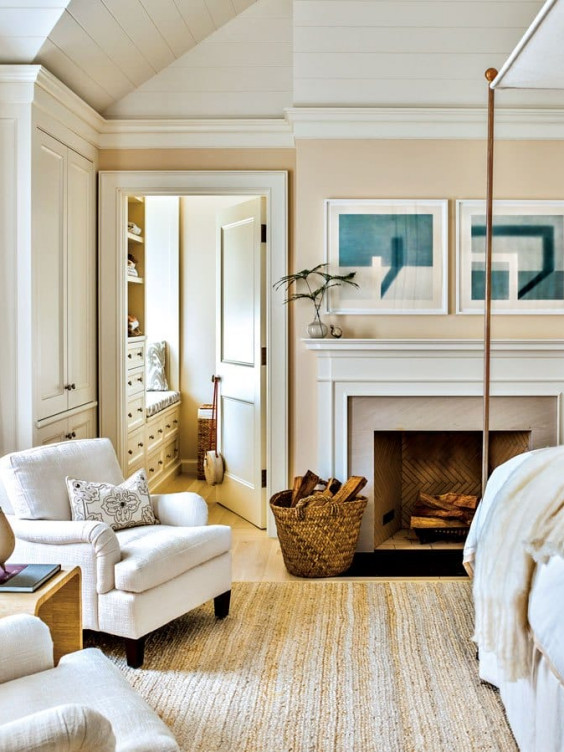 Cozy living room with armchair, fireplace, art on wall, and open door to storage space with shelves.