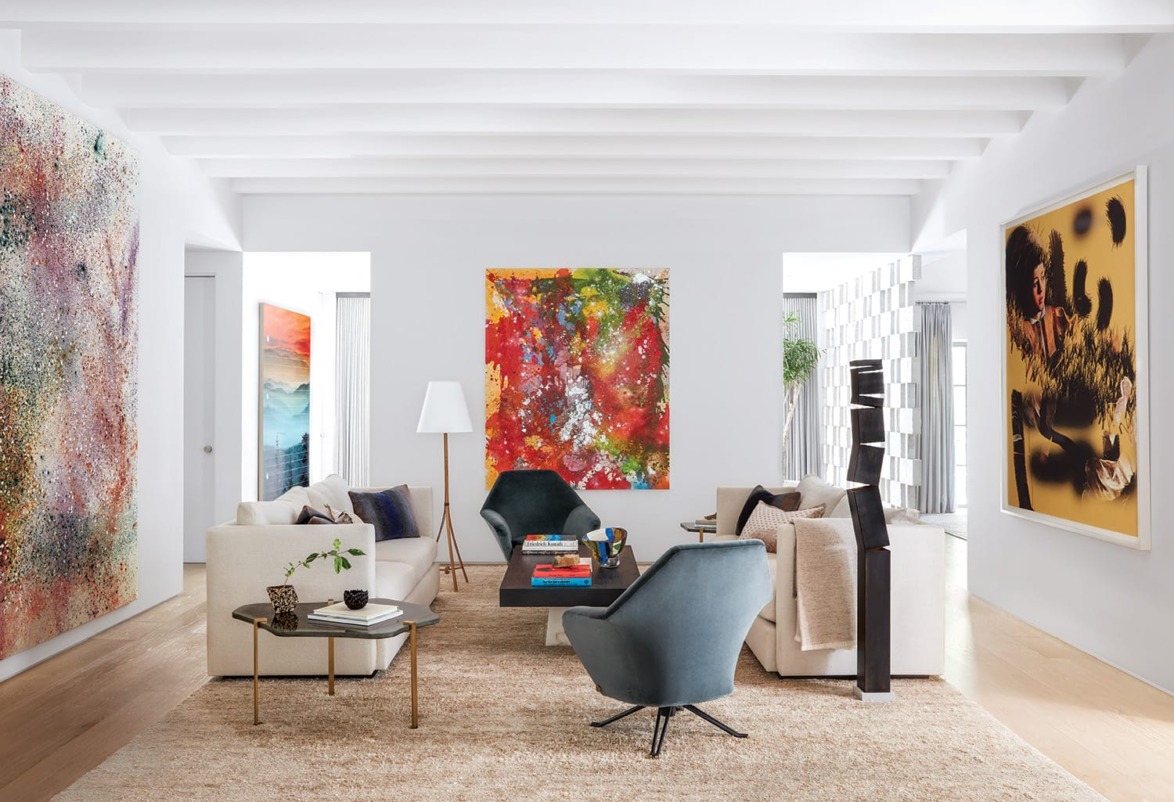 Modern living room with colorful abstract art, neutral furniture, and large windows allowing natural light to fill the space.