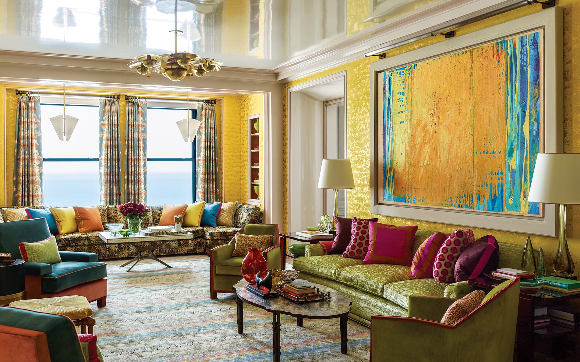 Colorful living room with vibrant sofas, patterned rugs, large abstract painting, and ceiling lights.