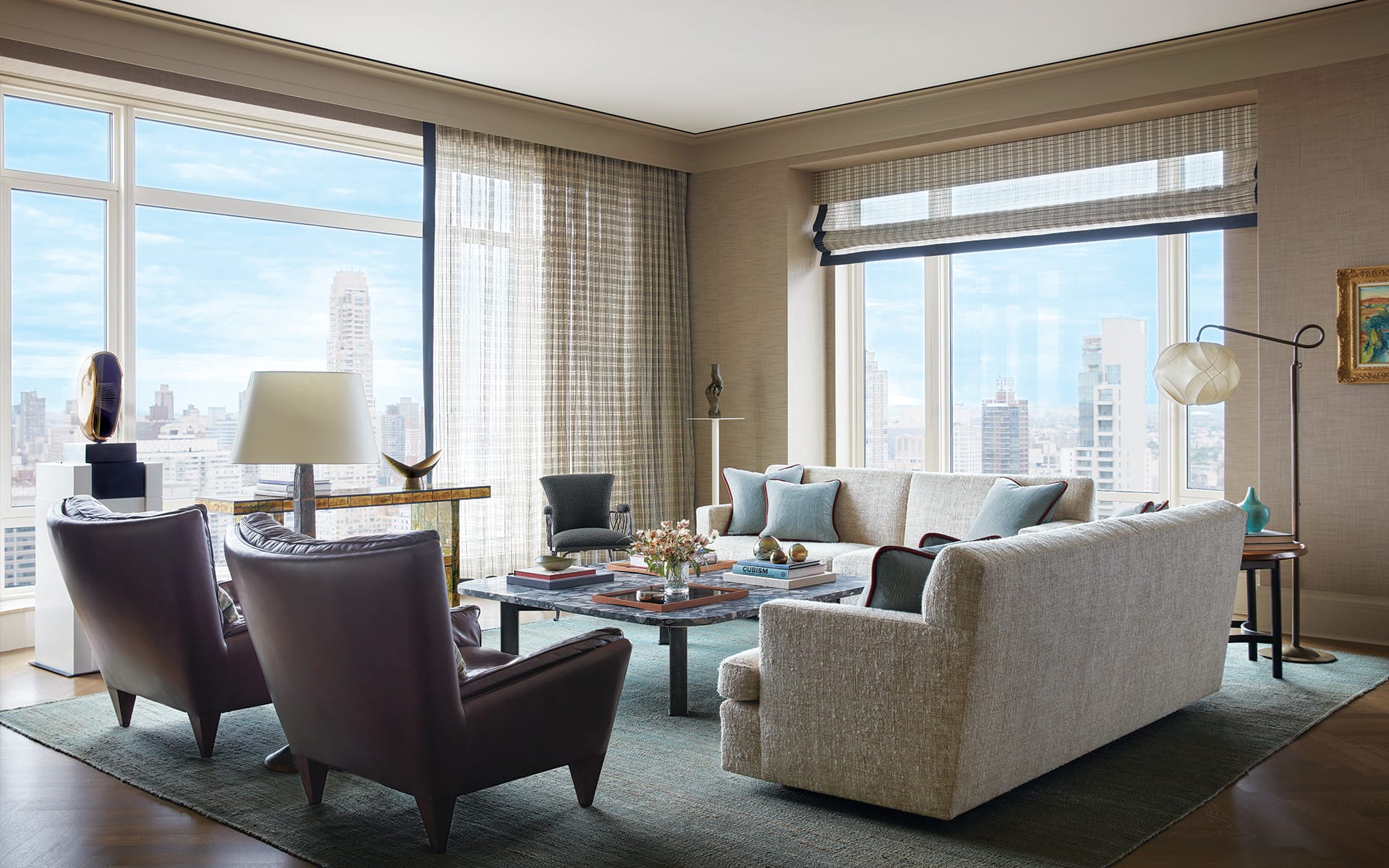 Elegant living room with large windows offering a city view, featuring modern furniture and a neutral color palette.