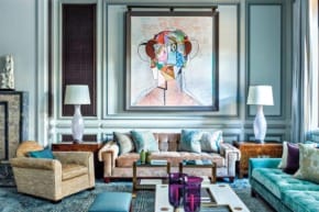 Stylish living room with eclectic art, plush sofas, lamps, and modern decor elements creating a cozy and vibrant atmosphere.