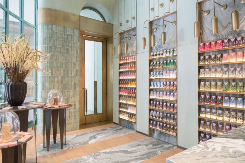 Colorful interior of a modern store with neatly displayed merchandise on shelves, elegant decor, and large vases with flowers.