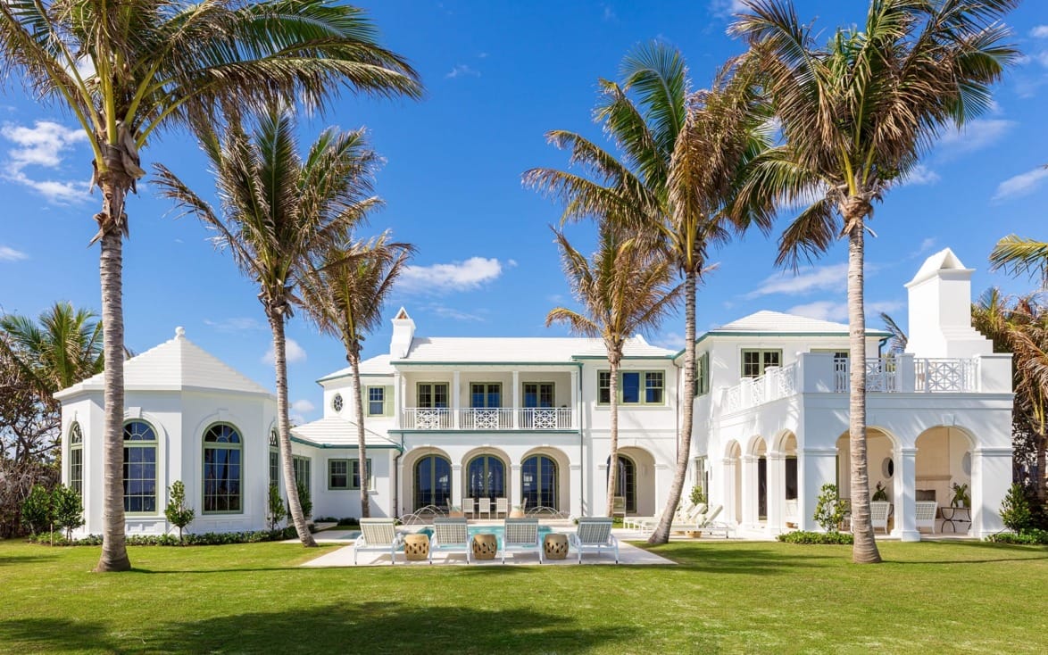 luxurious white mansion with palm trees and clear blue sky