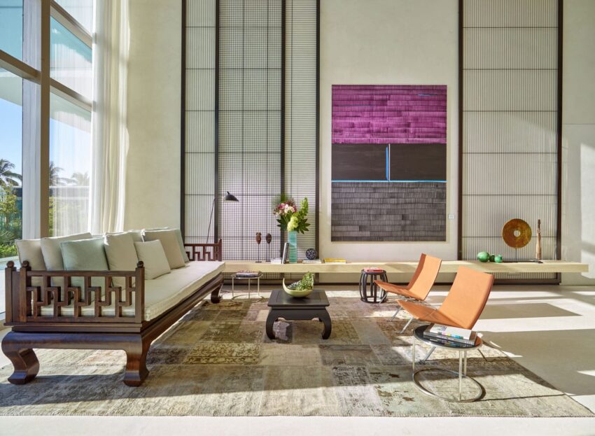 Modern living room with large abstract paintings, contemporary furniture, and natural light streaming through tall windows.