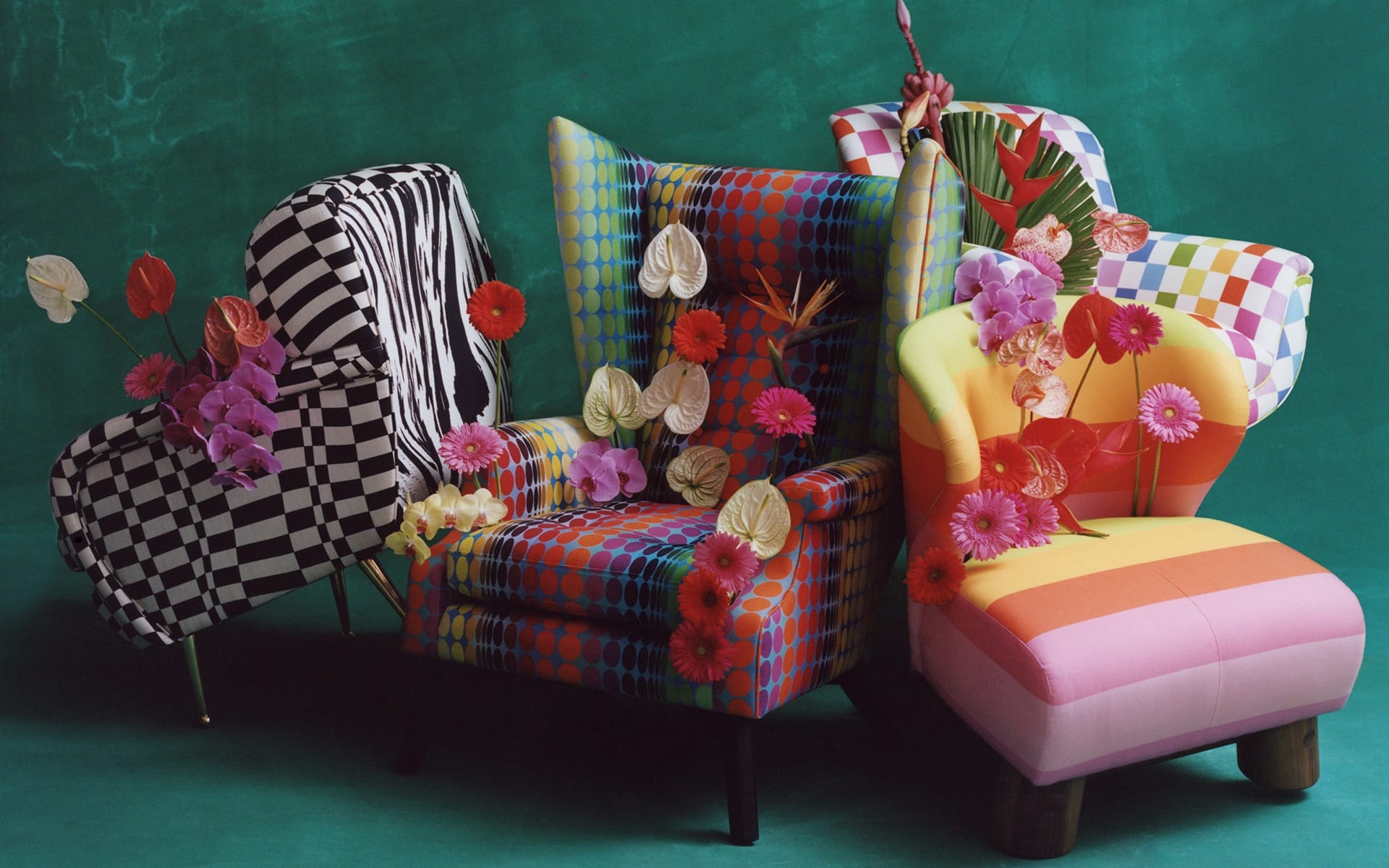 Colorful patterned chairs adorned with flowers against a green background.