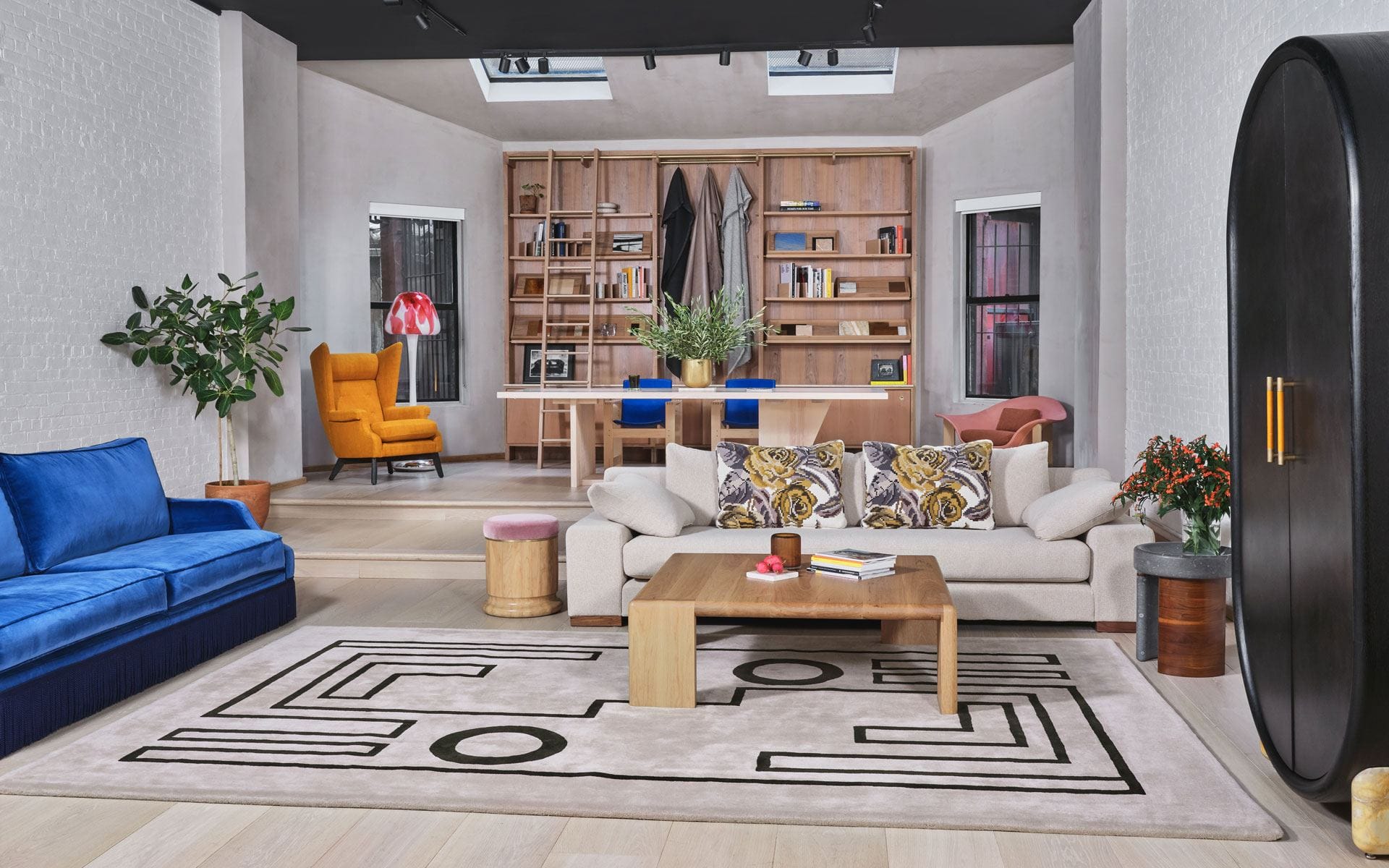 Modern living room with colorful couches, geometric rug, and wooden shelves in a bright, stylish interior space.
