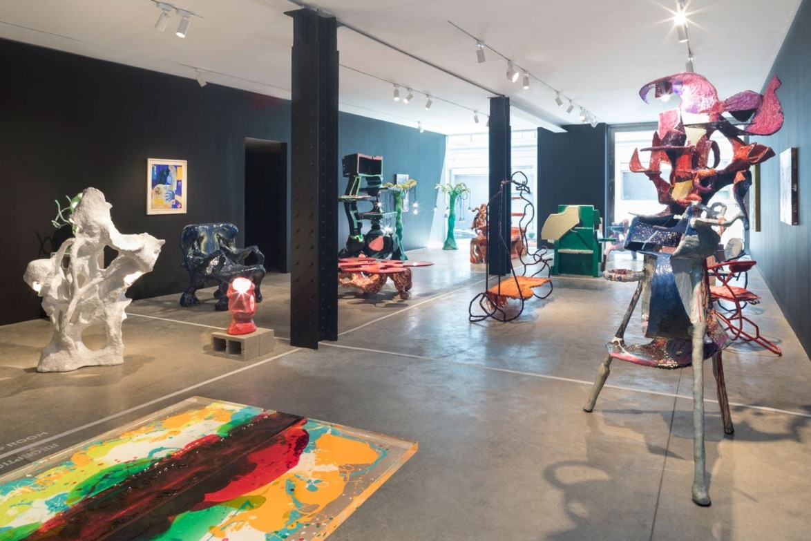 Contemporary art gallery with diverse abstract sculptures and paintings on display, featuring colorful and eclectic designs.