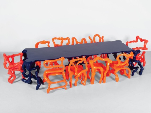 Abstract table with vibrant orange and blue chairs featuring unique, twisting designs.