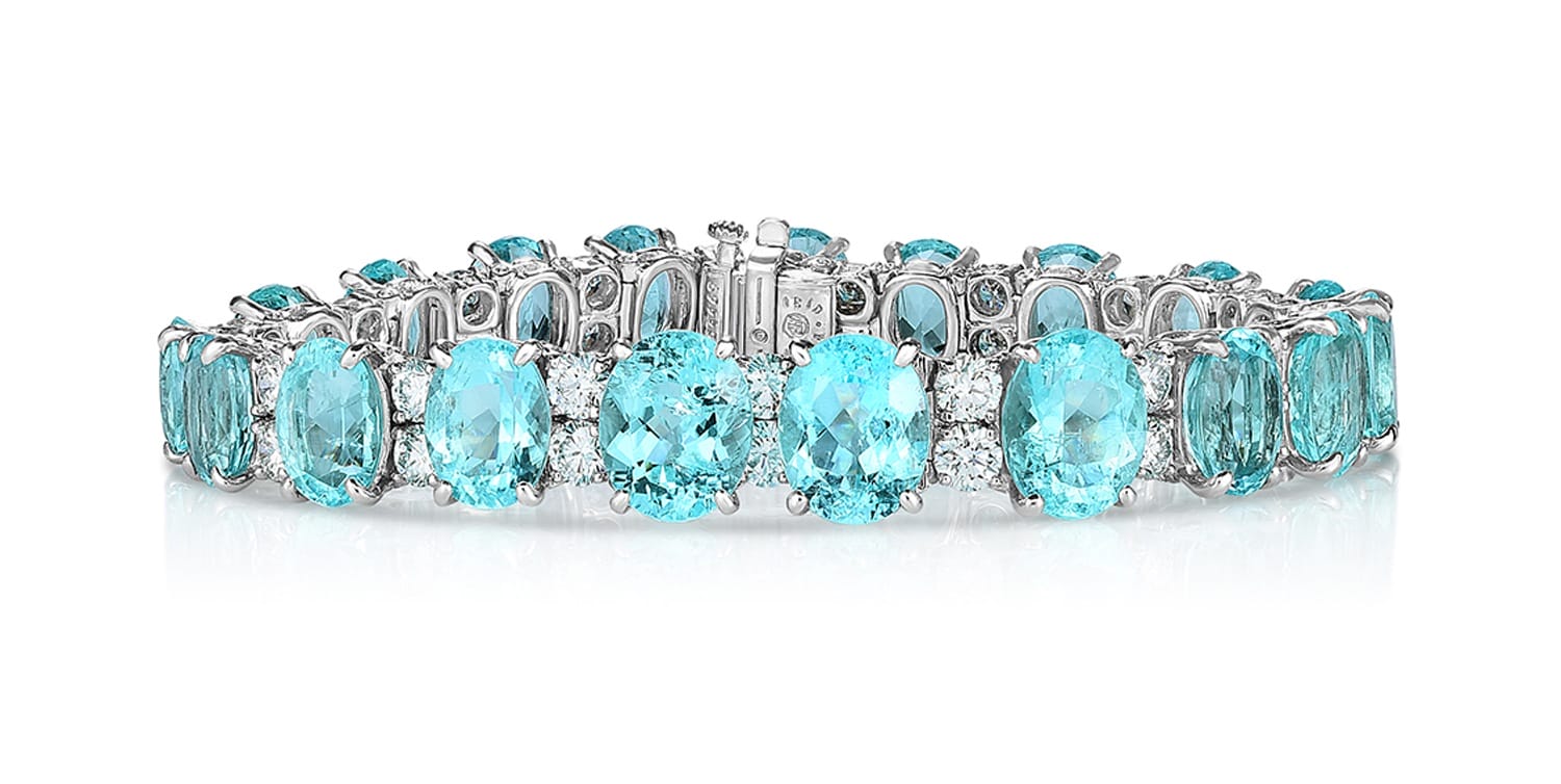 Silver bracelet with oval aquamarine gemstones and small diamond accents on a white background.