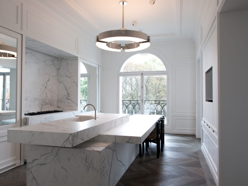 Modern kitchen with marble countertops, contemporary lighting, and large windows with a view, designed in a minimalist style.