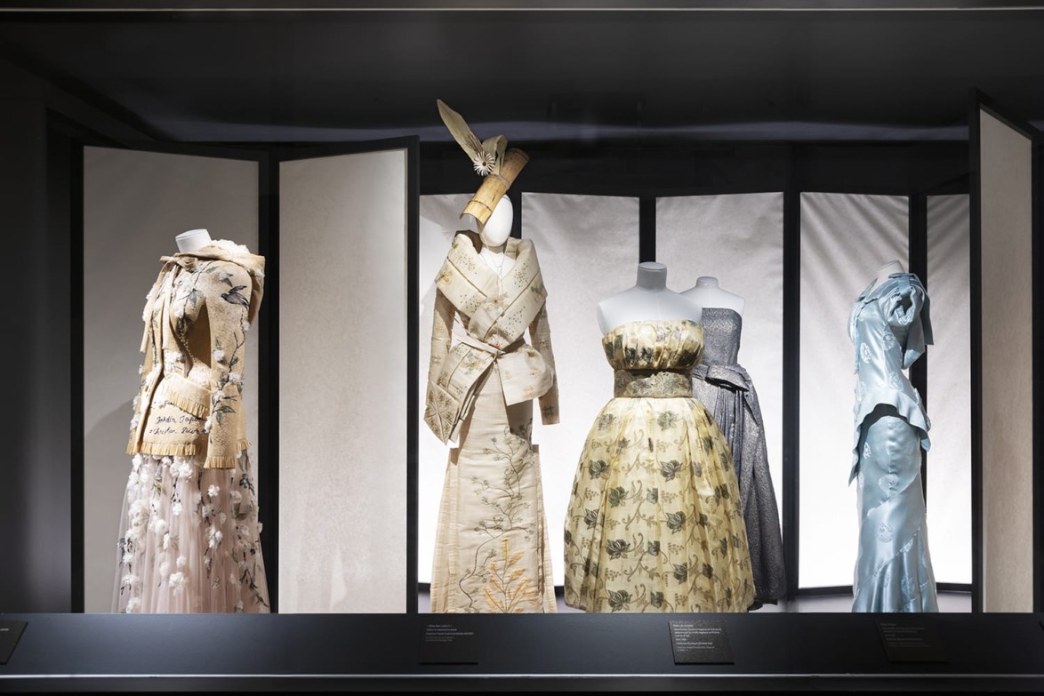Exhibition display of elegant, historical-style dresses and gowns on mannequins, showcasing intricate designs and textiles.