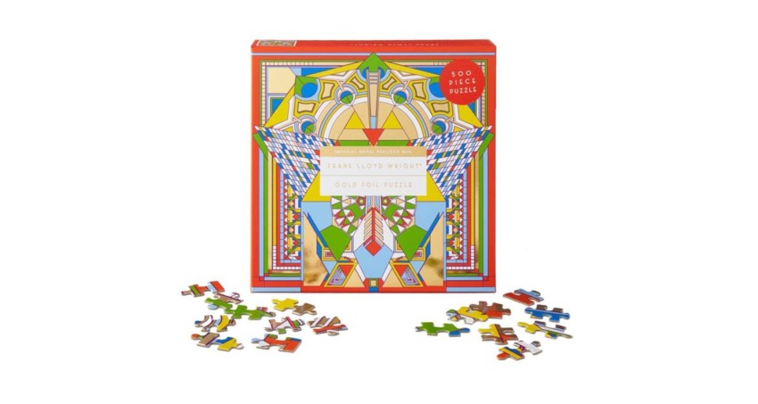 Colorful Frank Lloyd Wright gold foil puzzle box with scattered puzzle pieces around it.