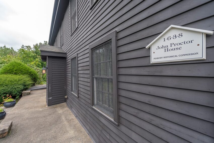 Exterior of a historic dark grey wooden house with sign marking it as part of the Peabody Historical Commission.