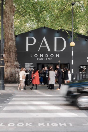 People gathered outside the PAD London art and design event, with a zebra crossing and trees in the background.