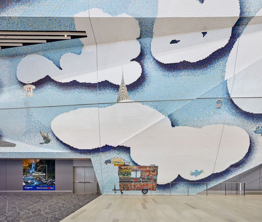 Colorful cloud-themed mural with hot dogs cart and bird on a building interior wall near an entrance.