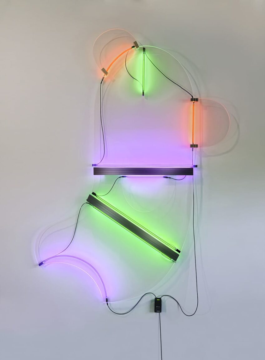 Neon light art installation with abstract shapes in orange, green, pink, and purple against a white wall.