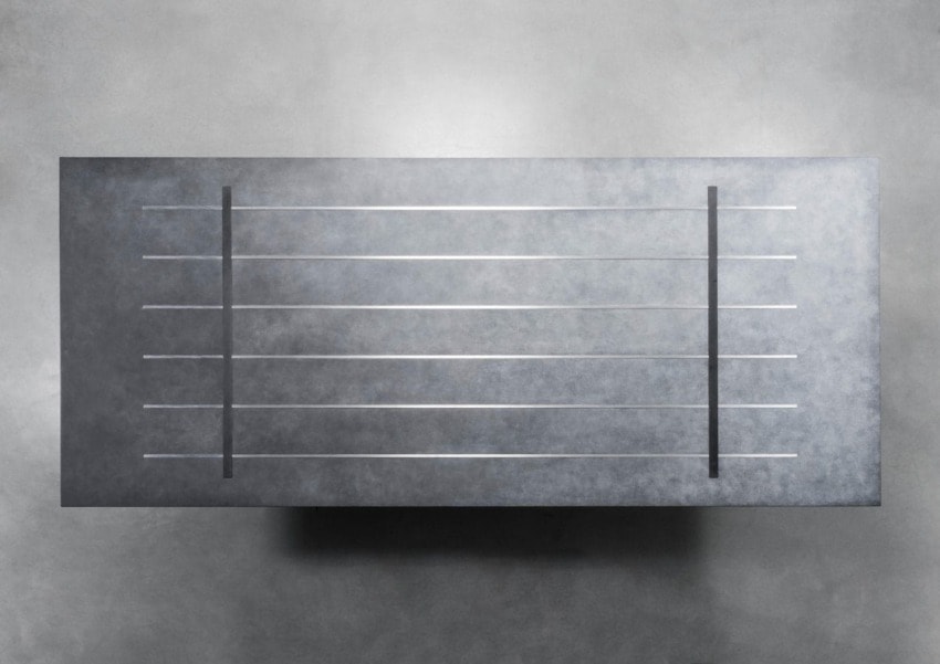 Abstract metallic wall art with horizontal lines and vertical dividers against a textured gray background.