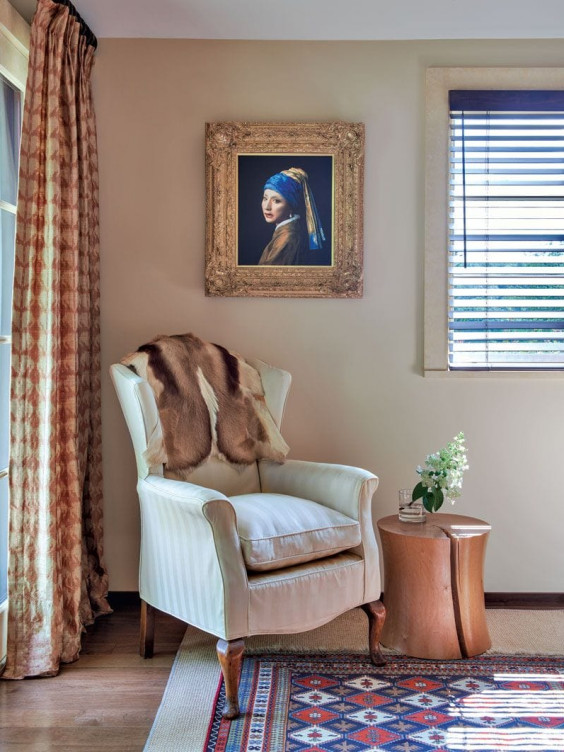 Elegant sitting area with white armchair, small wooden table, and a framed portrait on the wall.