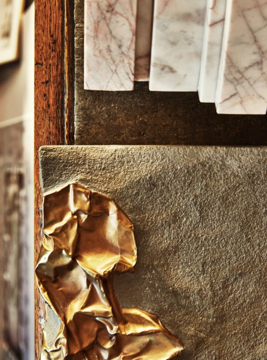 Various textured materials, including polished marble, raw stone, and crumpled gold foil, in an artistic arrangement.