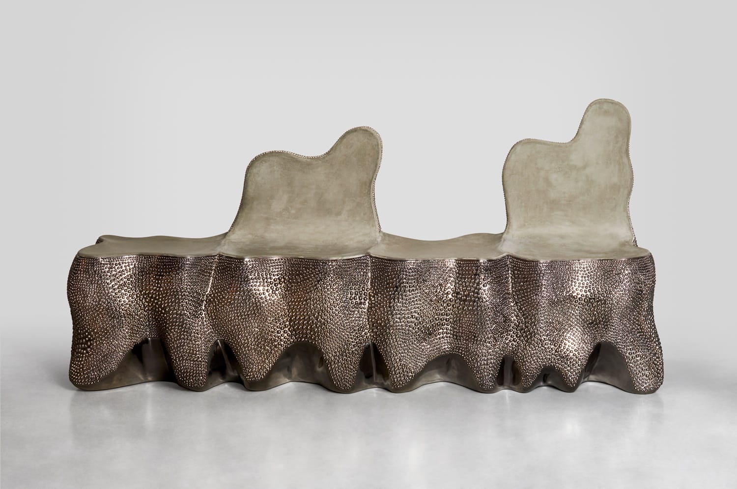 Modern abstract sculpture bench with textured metallic and smooth surfaces, featuring two irregular-shaped backrests.
