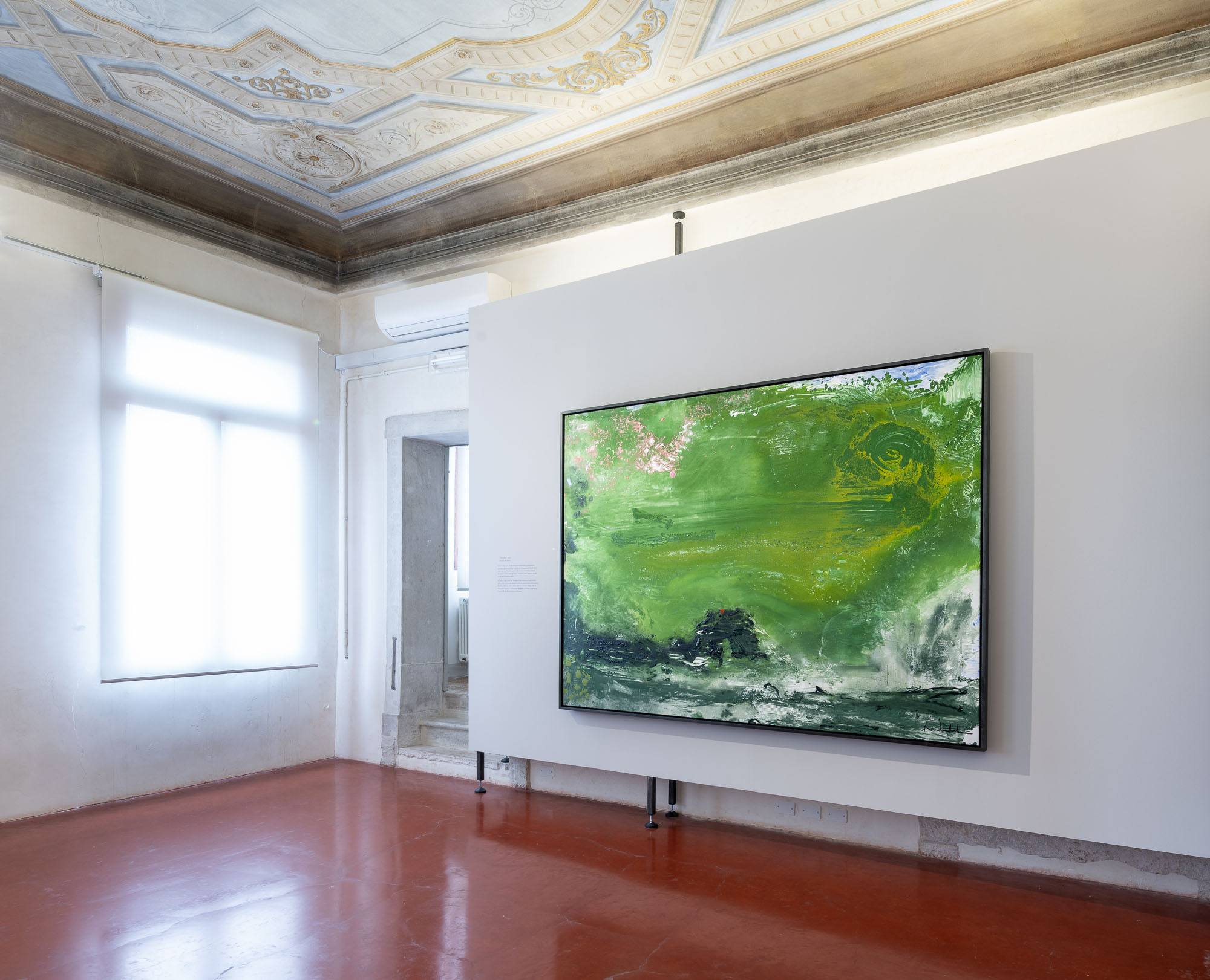 Painting in a gallery with ornate ceiling, featuring bright green and dark tones on a large canvas.
