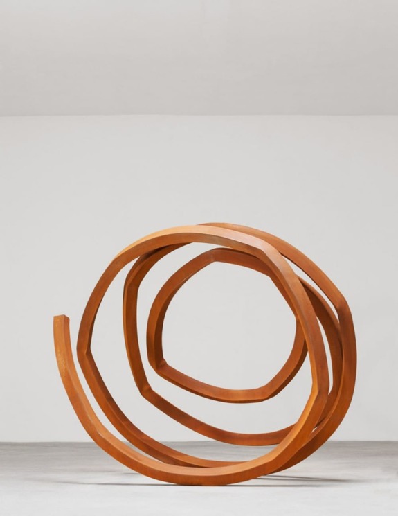 Large abstract wooden spiral sculpture on a white background.