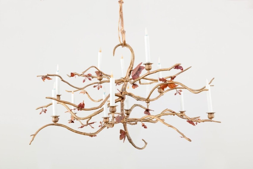 Elegant chandelier with twisty branches and candle-like bulbs adorned with delicate leaf and butterfly designs.