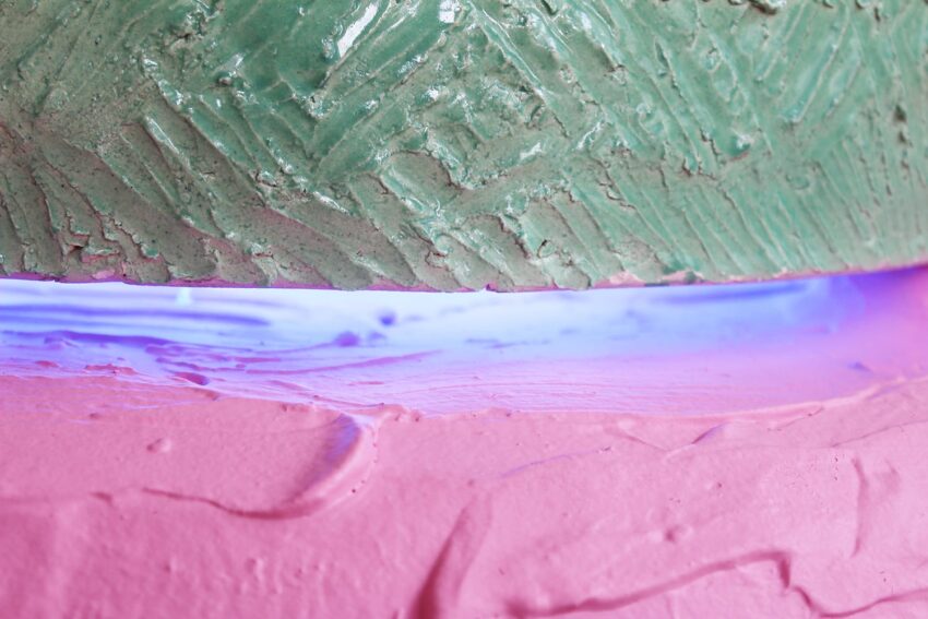 Close-up of a textured green and pink surface with a glowing purple light in between, creating a vibrant abstract scene.