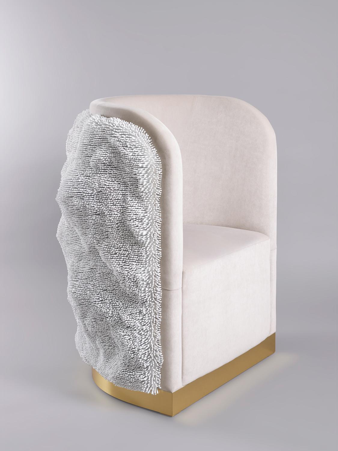 Elegantly designed modern chair with unique textured fabric side and gold metallic base on a gray background.