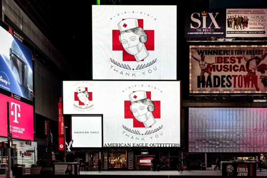 Times Square displays thank you message to nurses with vintage nurse image and red cross, surrounded by bright advertising signs.