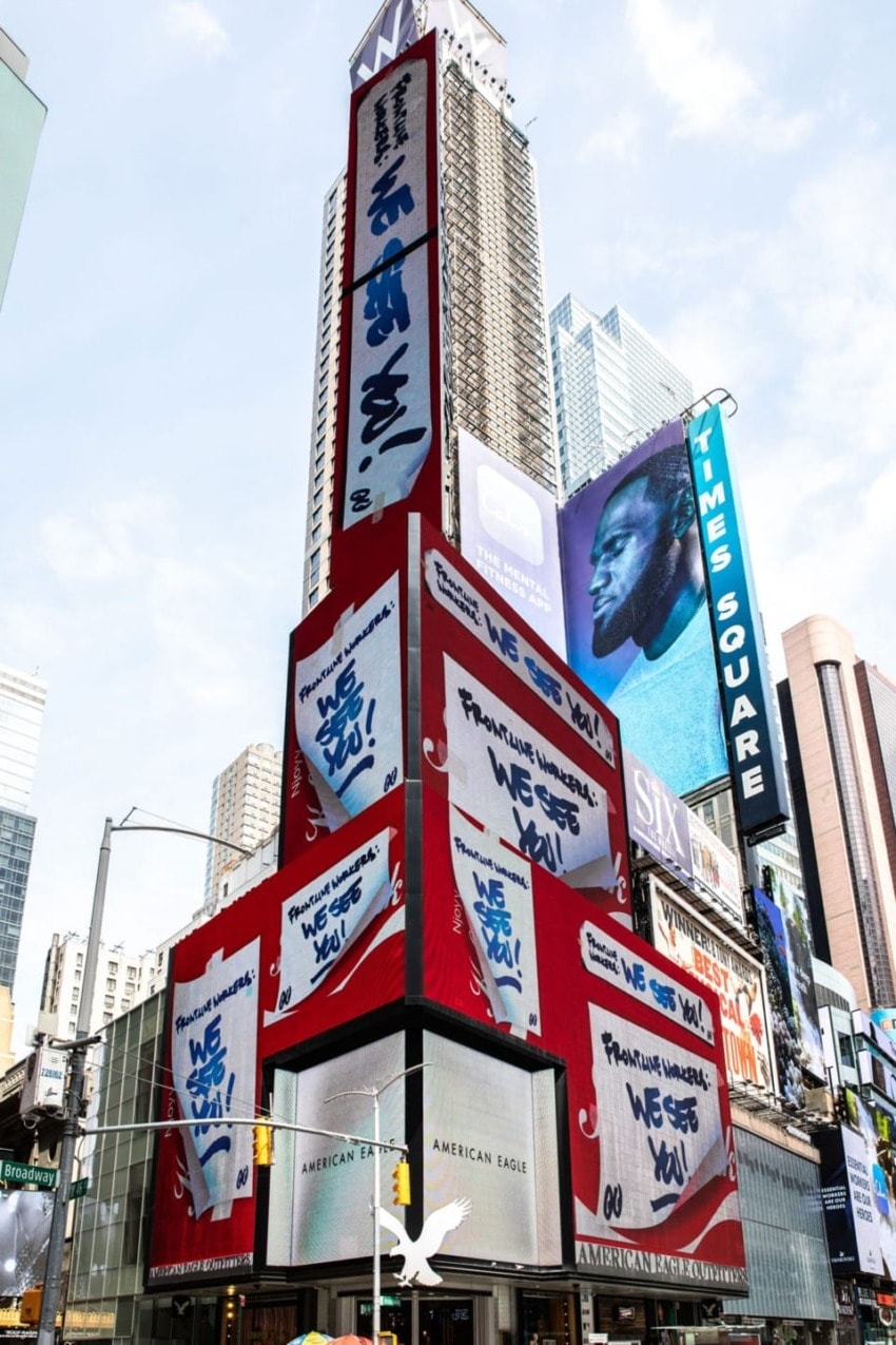 Times Square billboards displaying various advertisements and street signs with tall buildings in the background.