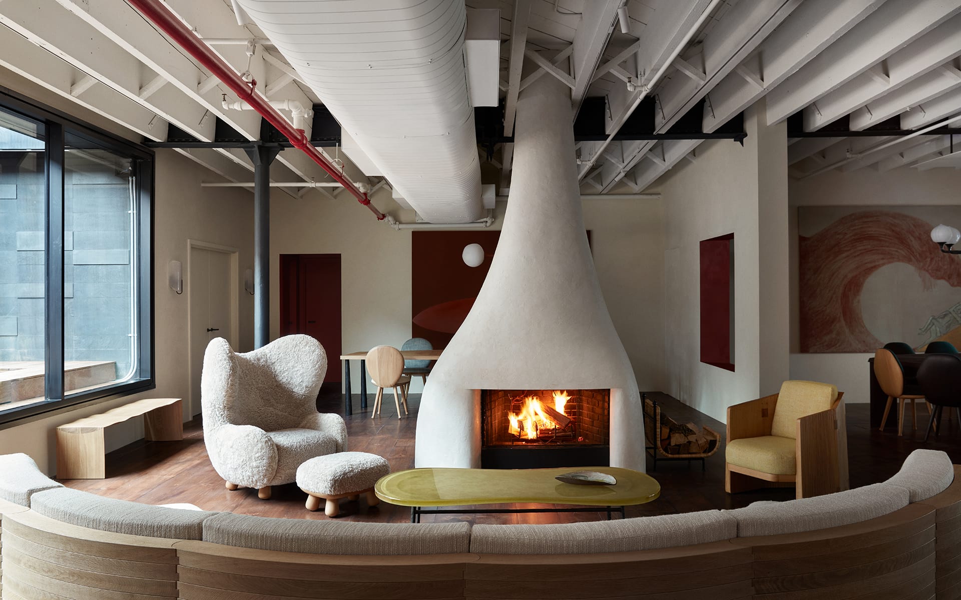 Modern living room with unique cone-shaped fireplace, plush chairs, wooden table, and exposed ceiling beams.