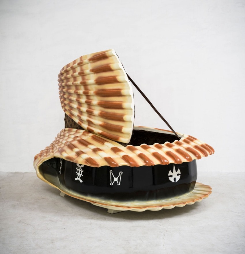 Decorative clamshell bed with intricate designs on a plain background.