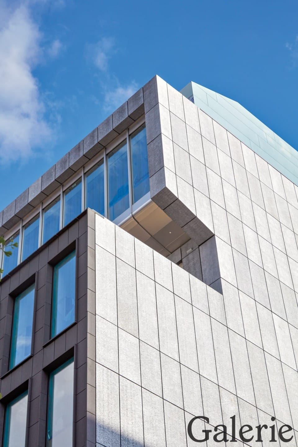 Modern building facade with large windows against a clear blue sky.