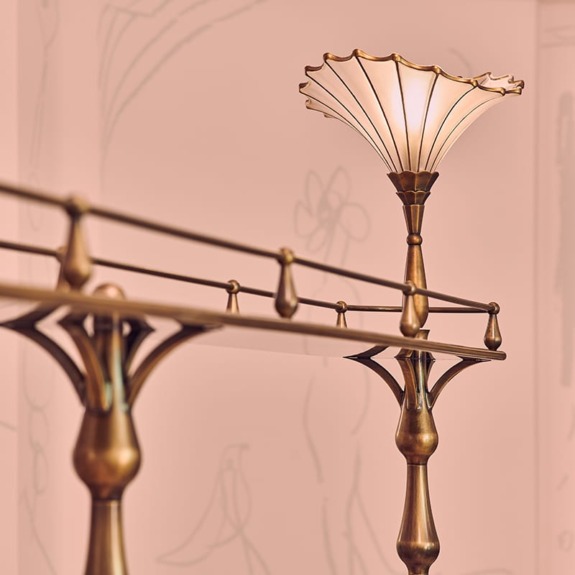 Vintage brass lamp with a fluted glass shade on a soft pink background.