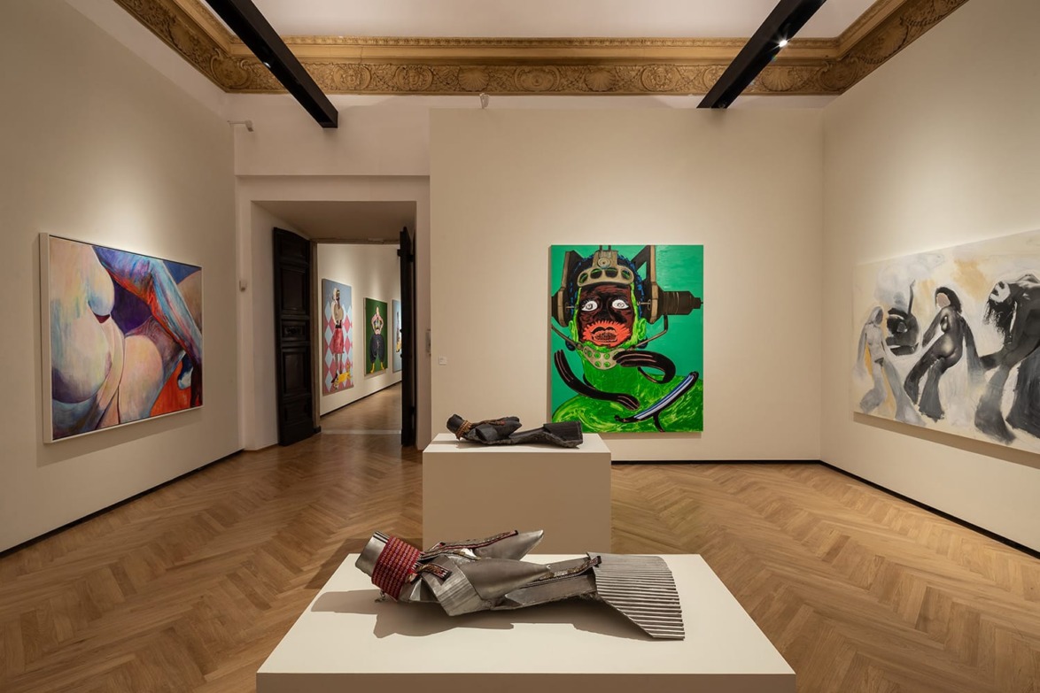 Contemporary art gallery with colorful paintings on the walls and abstract sculptures displayed on the wooden floor.