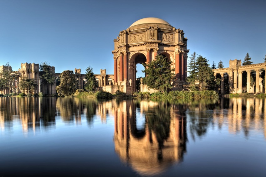Palace of Fine Arts in San Francisco with clear blue sky, reflecting on a tranquil lake in the foreground.